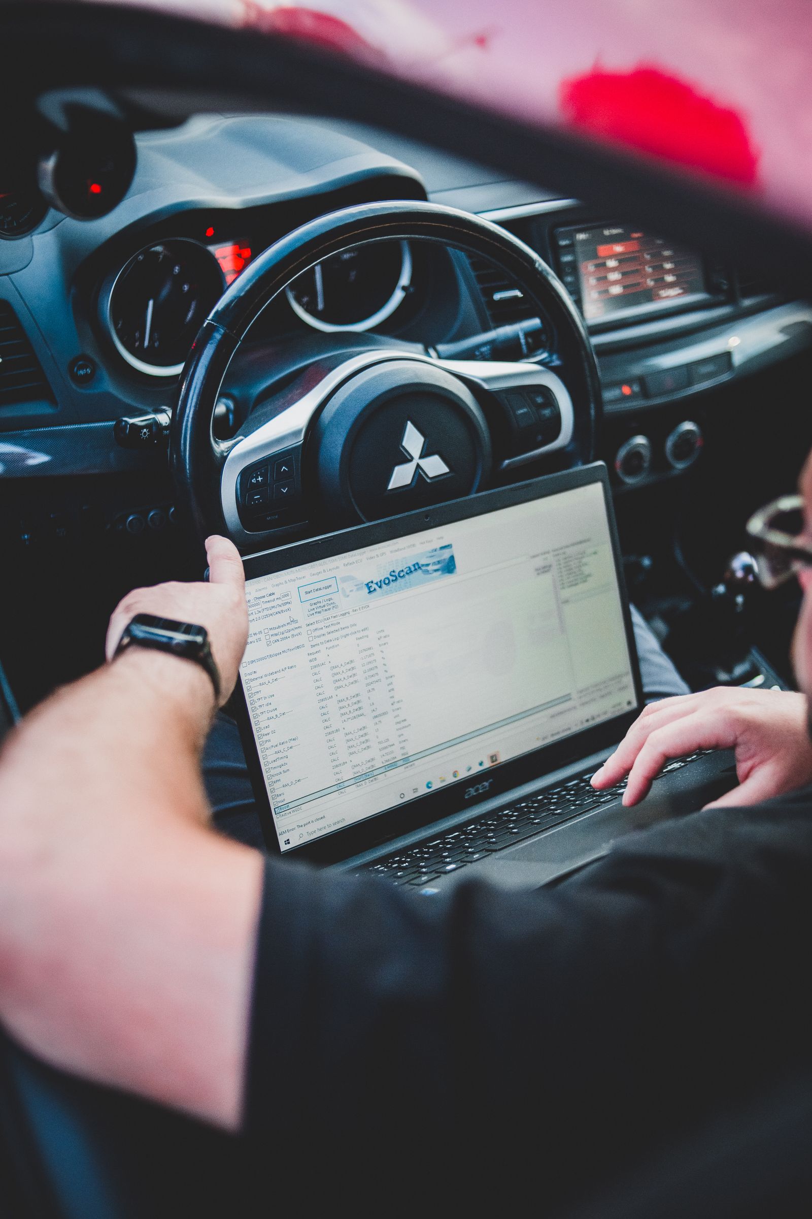 Technician using a laptop for vehicle diagnostics inside a car